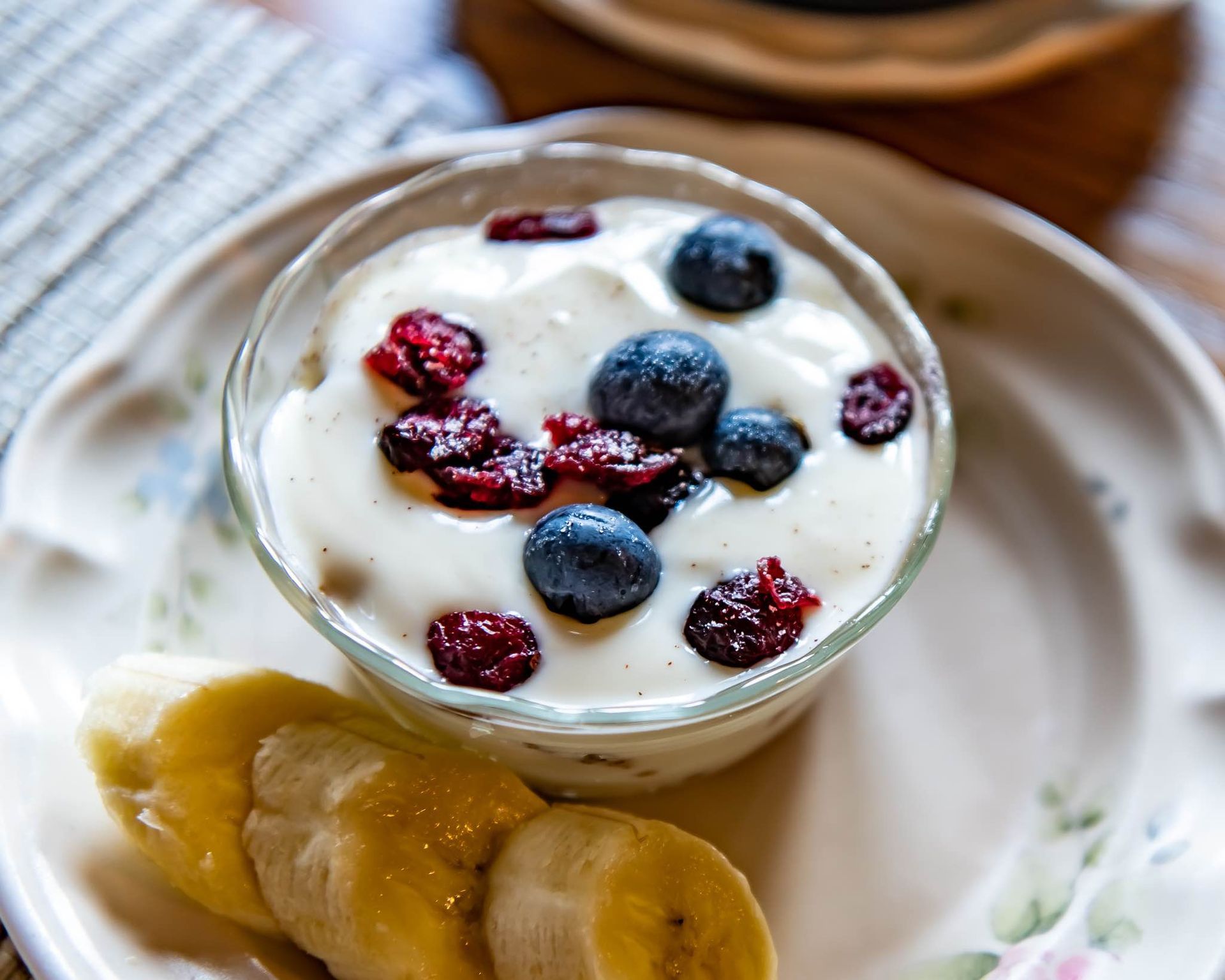 A bowl of yogurt with blueberries and bananas on a plate
