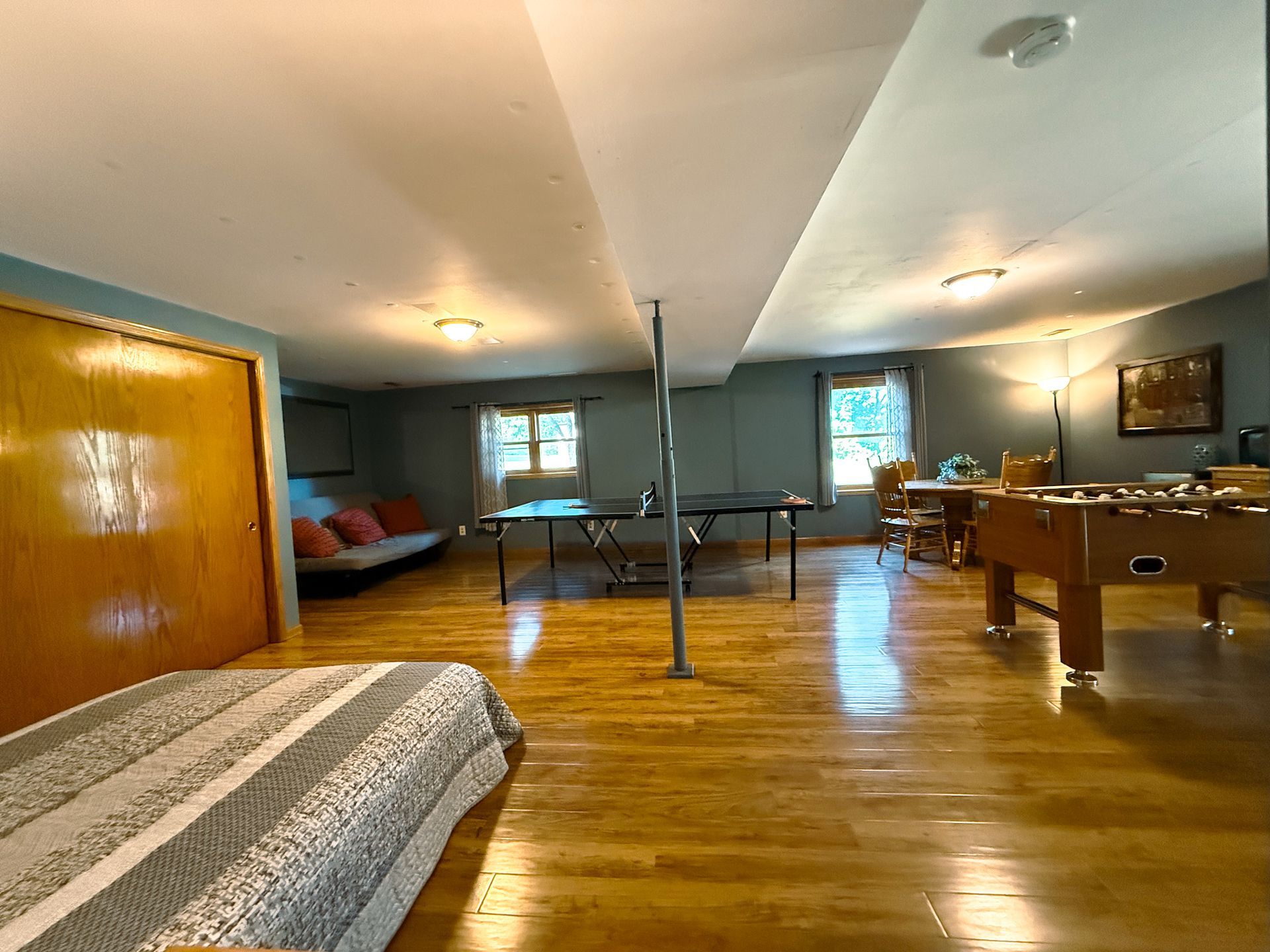 Spacious rec room with wood floors, a pool table, couch, and skylights.