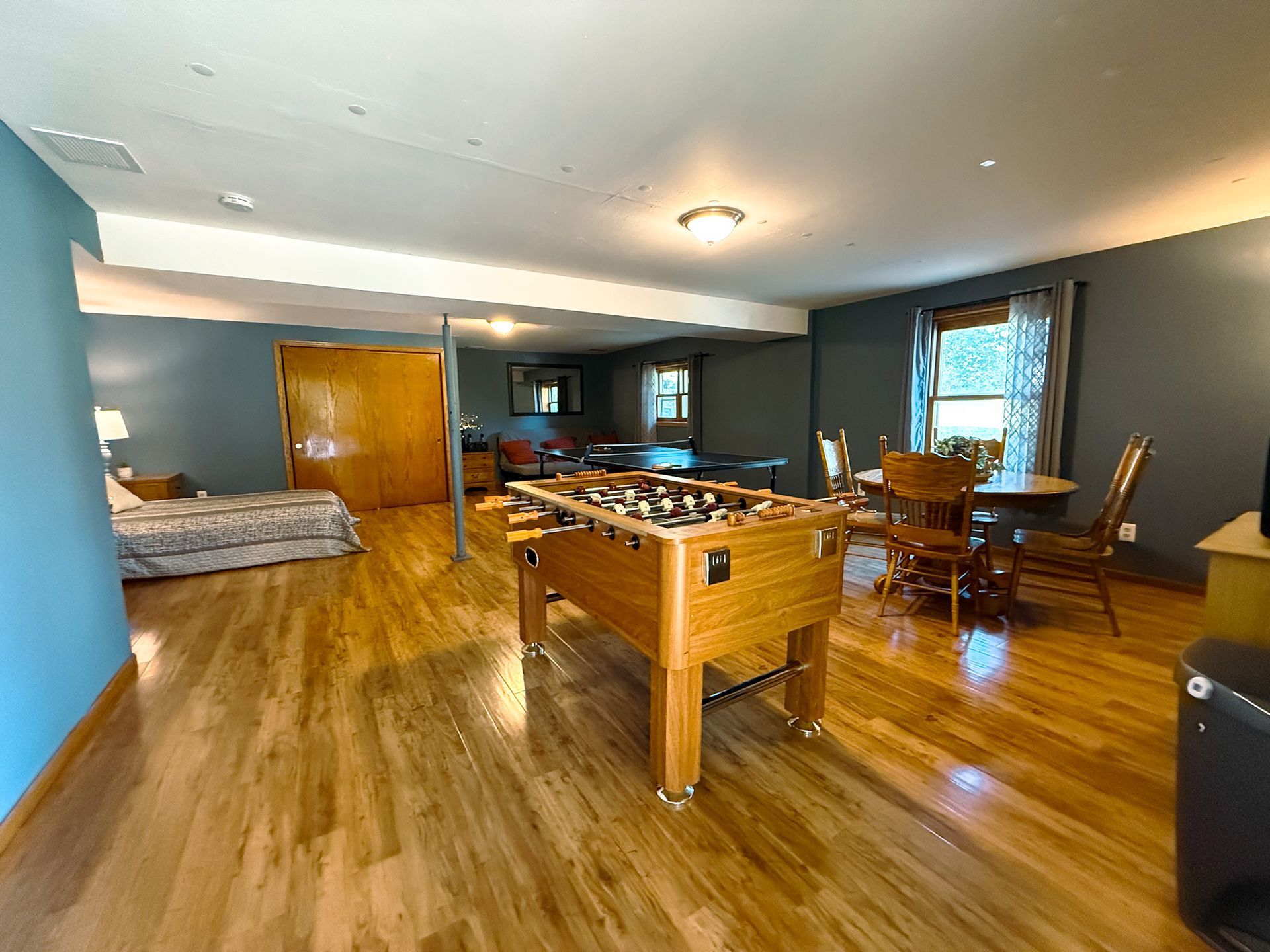 Recreation room with pool table, couch, desk, and large windows on wood floor