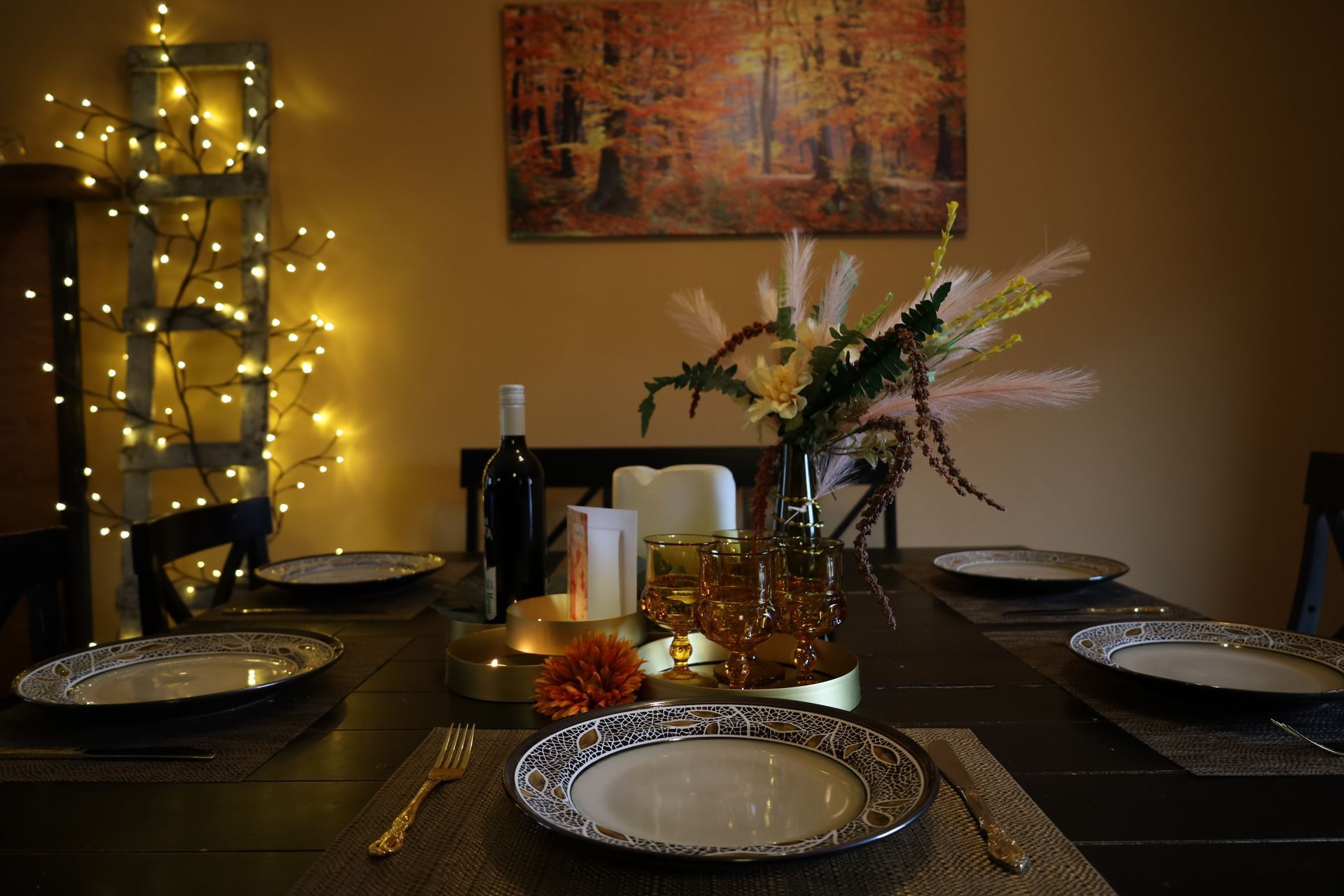 Set dining table with plates, candles, fairy lights, and a flower centerpiece in a warm-lit room