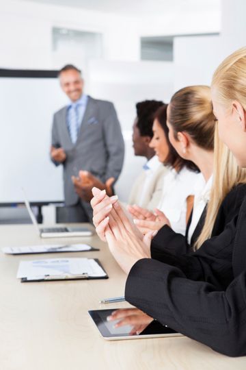 A man in a suit is giving a presentation to a group of business people