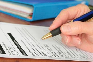 A person is filling out a form with a pen