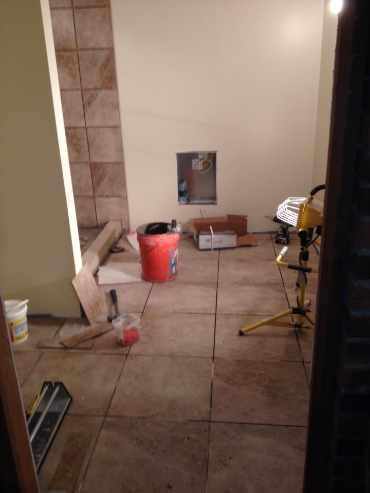 A room with tile floors and a red bucket on the floor