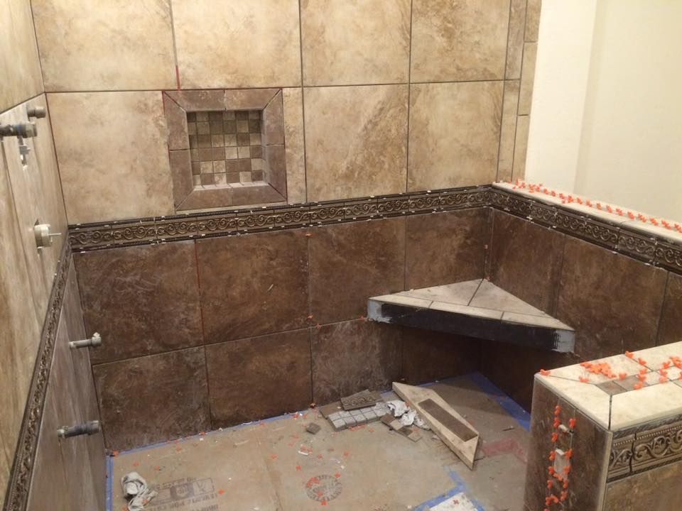 A bathroom with tiled walls and a corner bench.