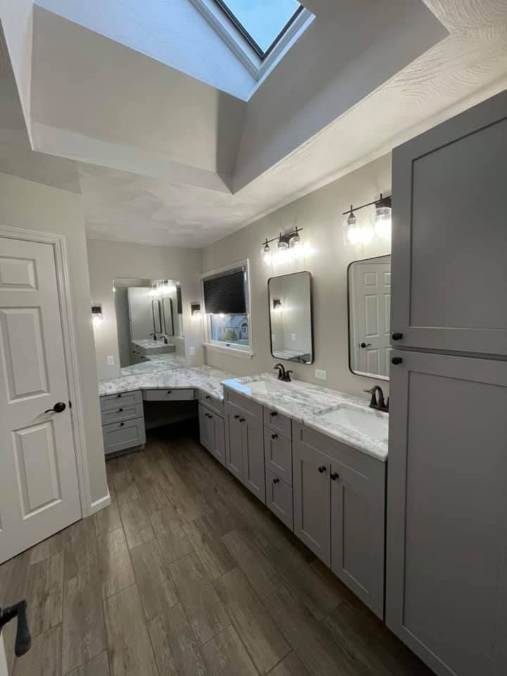 A bathroom with two sinks , two mirrors , and a skylight.