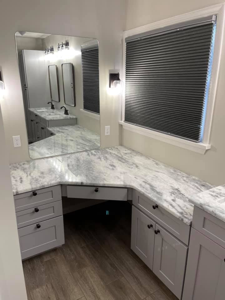 A bathroom with a vanity , sink , mirror and marble counter tops.