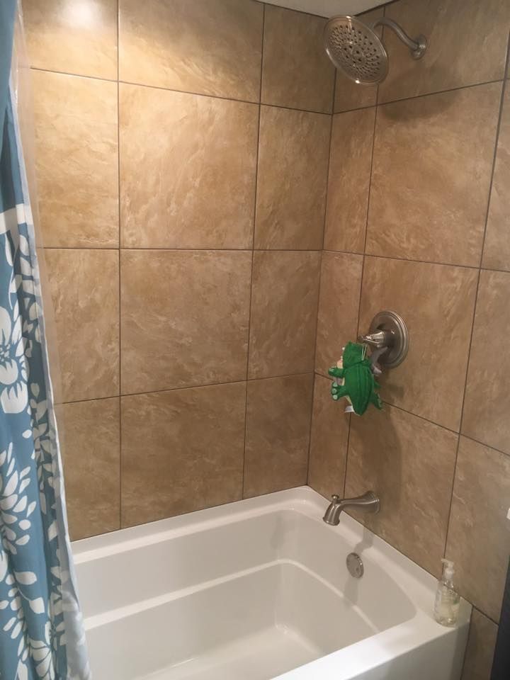 A bathroom with a bathtub , shower , and tiled walls.