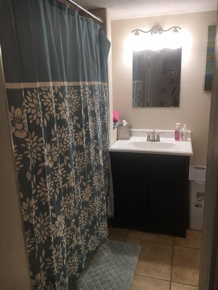 A bathroom with a shower curtain , sink and mirror.