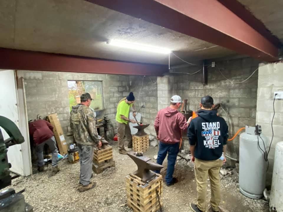 A group of men are working on an anvil in a garage.