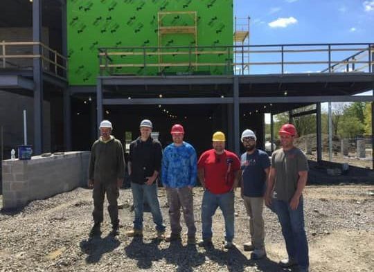 A group of construction workers are standing in front of a building under construction.