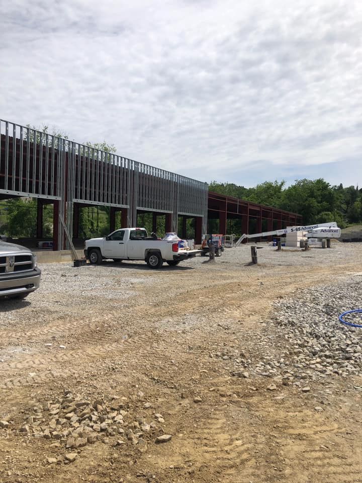 A white truck is parked in front of a building under construction.