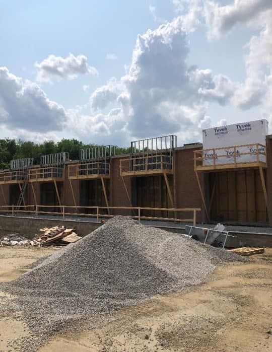 A building under construction with a pile of gravel in front of it.