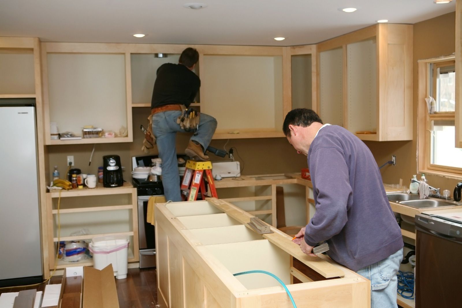 A man in a black hoodie is working on a machine.