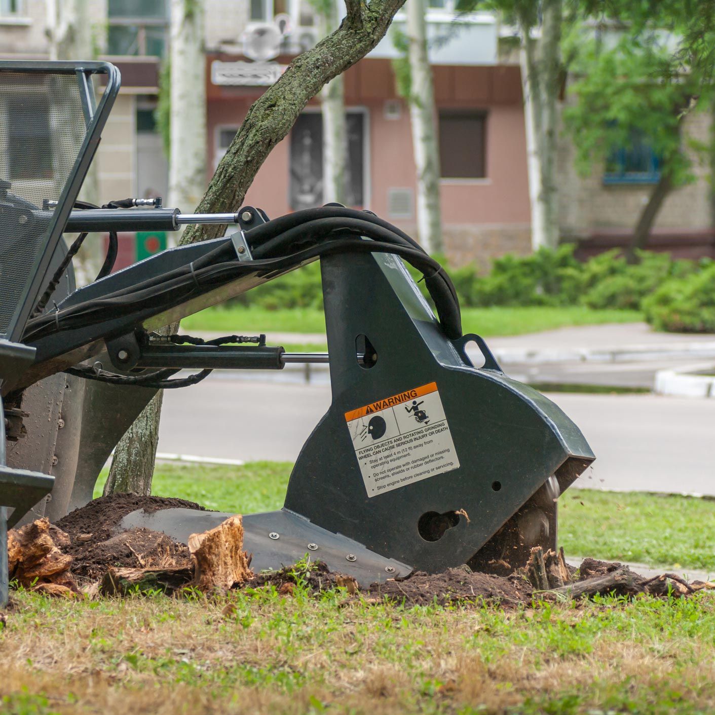 A tree stump is being removed by a machine in a park. A tree stump is being removed by a machine in a park.