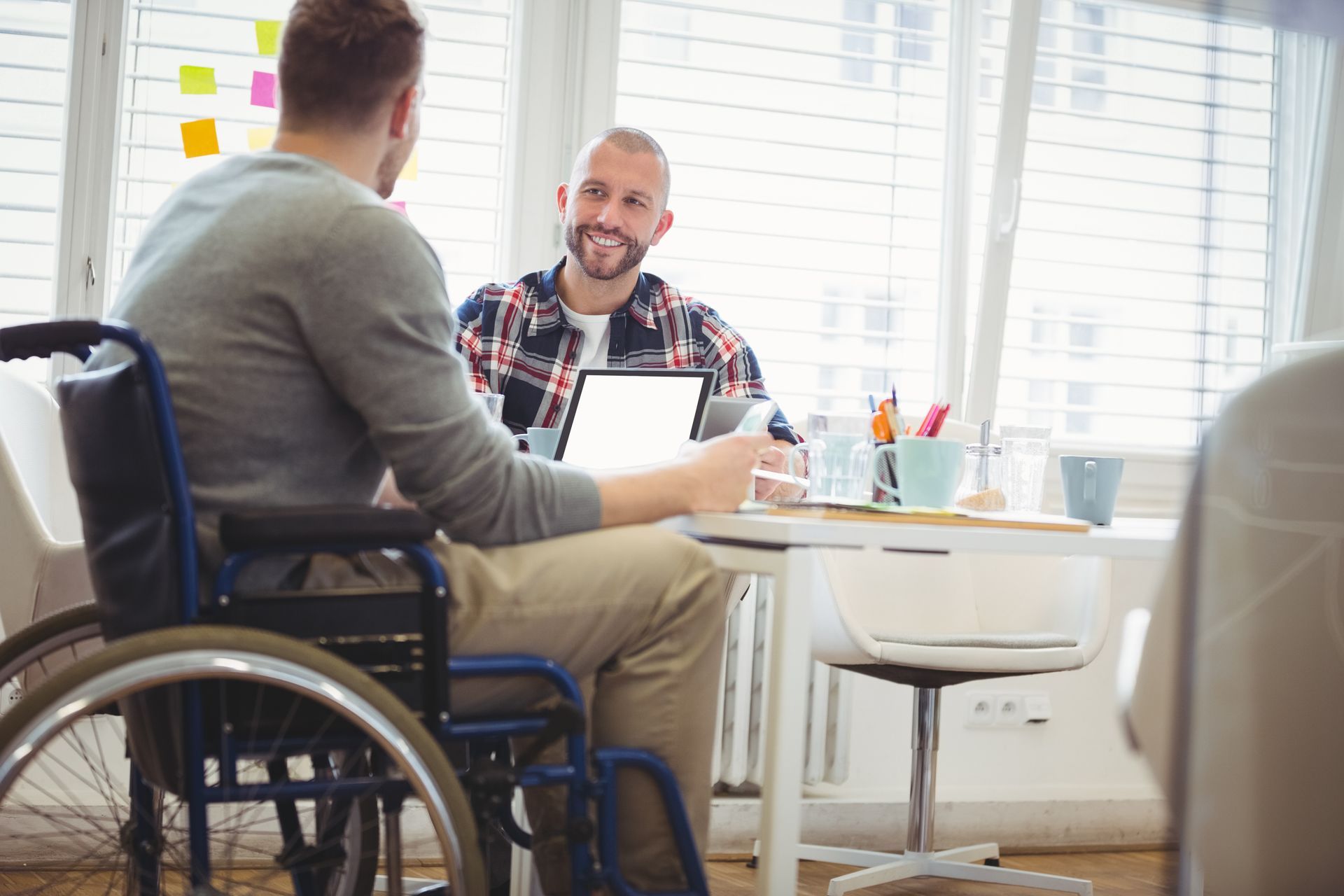 Man in Wheelchair at a Desk Conversing — Ani's Care Pty Ltd In Millner, NT