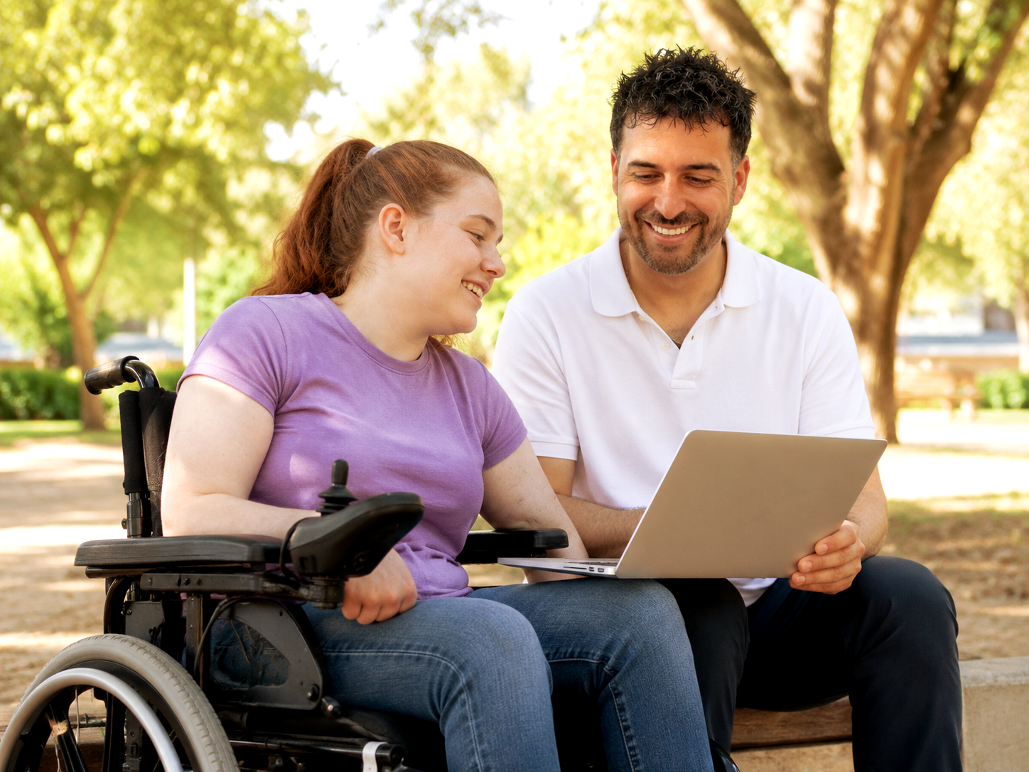 Jacob Cook, founder of JC Cornerstone, sitting with an NDIS participant in a wheelchair, looking at a laptop together