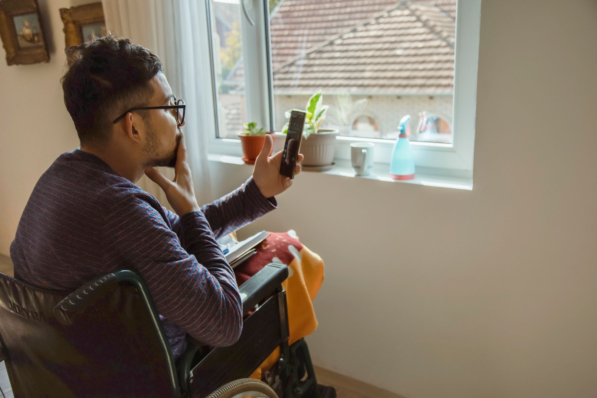 NDIS participant in a wheelchair, lonely, seeing if Psychosocial Recovery Coaching is right for him by reading up about it on his smartphone