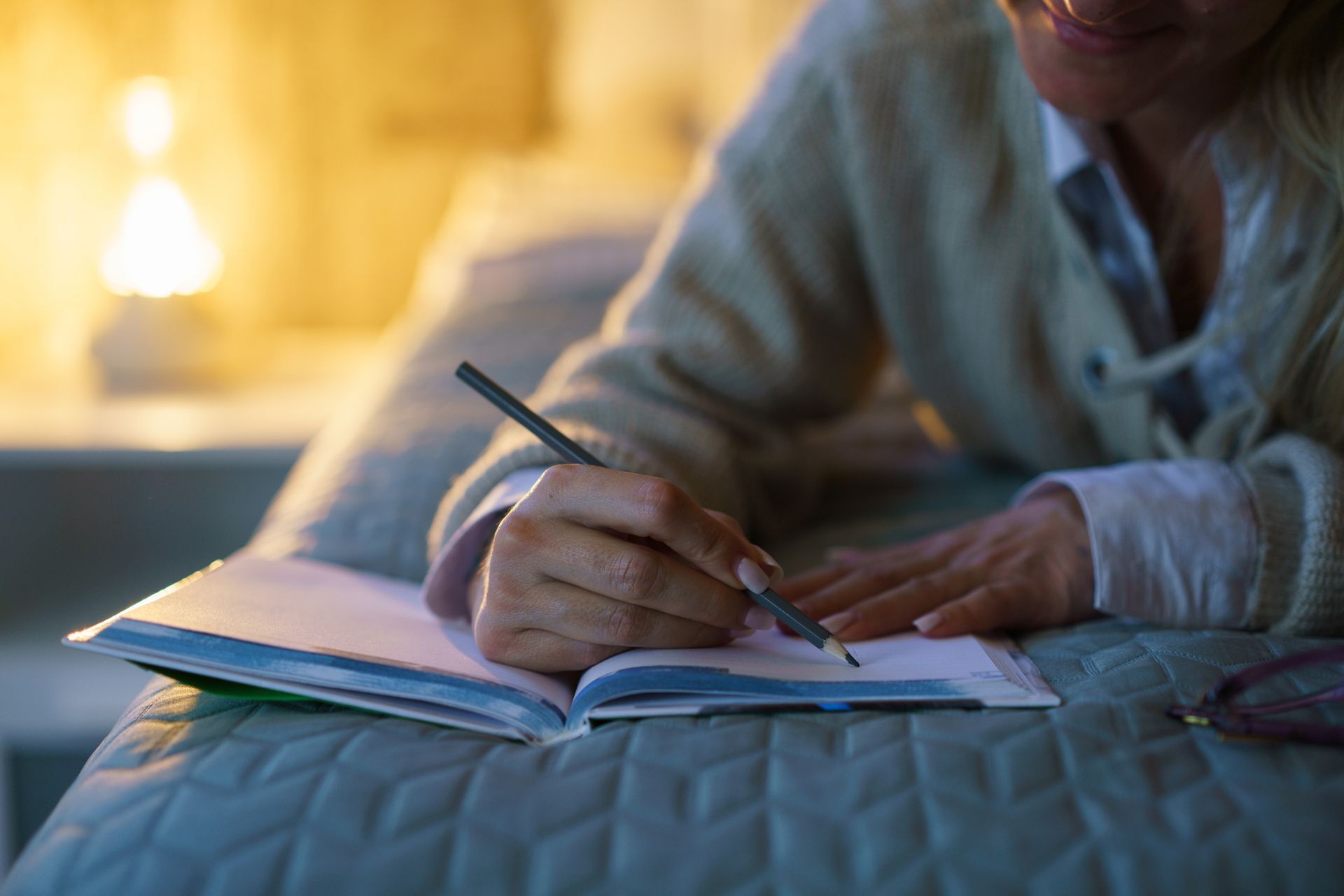 NDIS participant lying on bed with pen and notebook, planning goals after a Psychosocial Recovery Coaching session