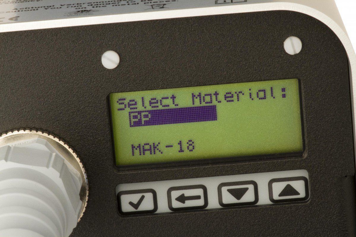 Primer plano de la pantalla de un dispositivo que muestra “¡Seleccione material!” y “EP”, con cuatro botones de navegación debajo.