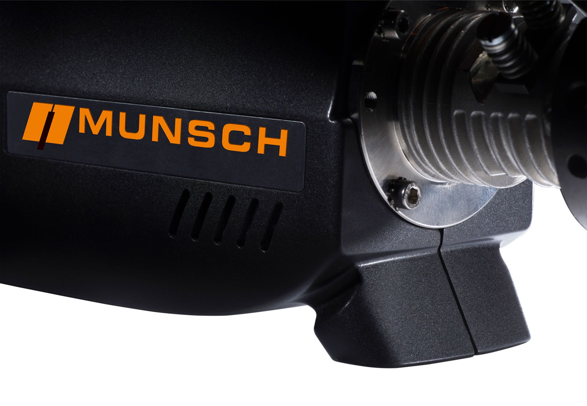 Primer plano de una herramienta o pieza de máquina Munsch negra con logotipo naranja y componentes metálicos plateados.