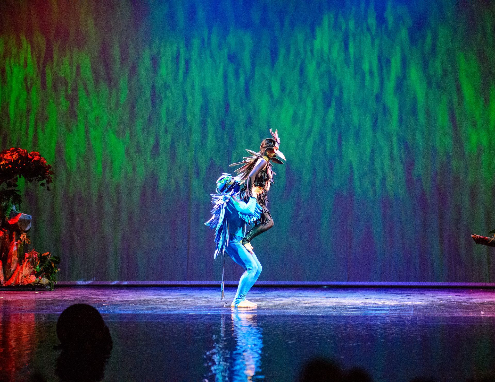 A couple of people are dancing on a stage in front of a colorful background.