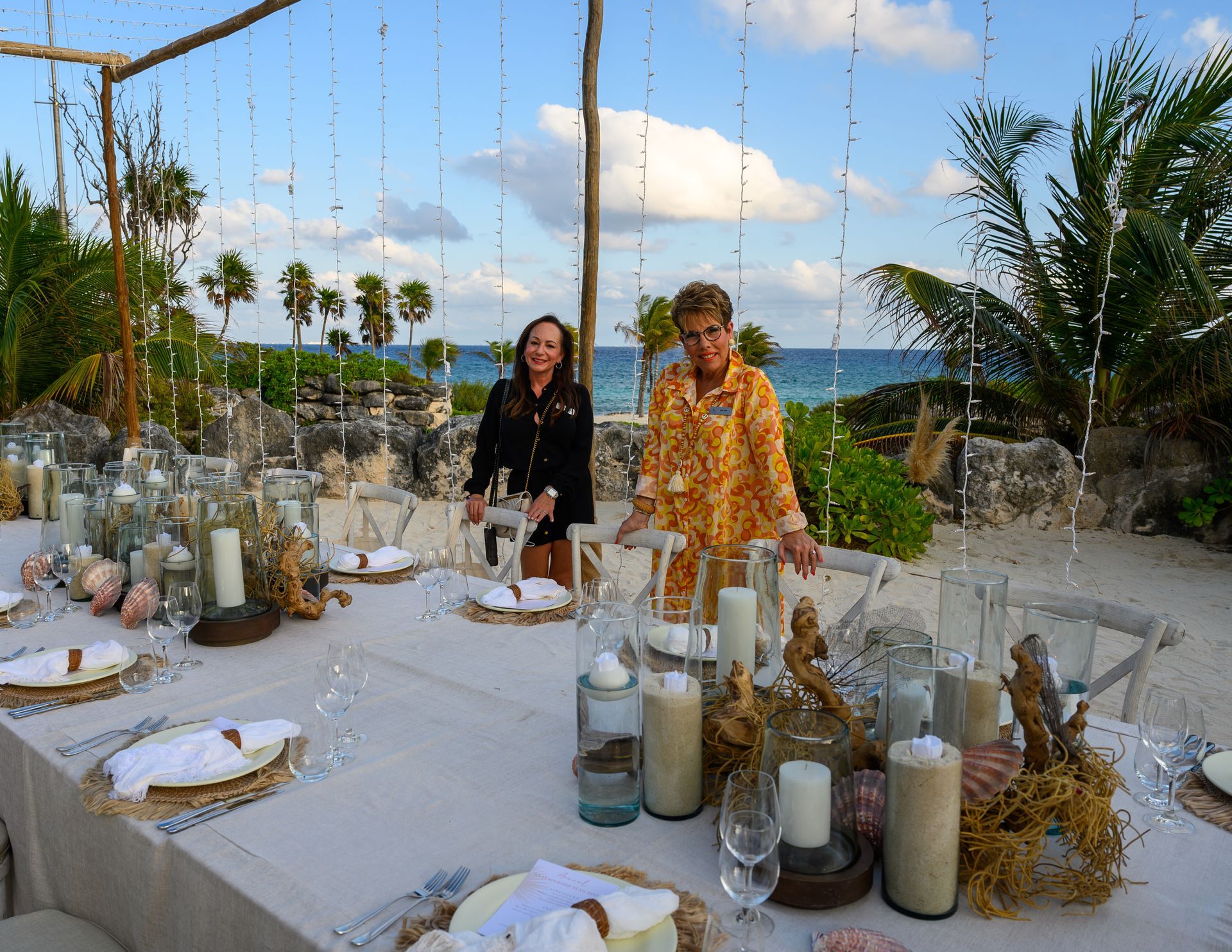 two women are standing next to a table set for a wedding reception .