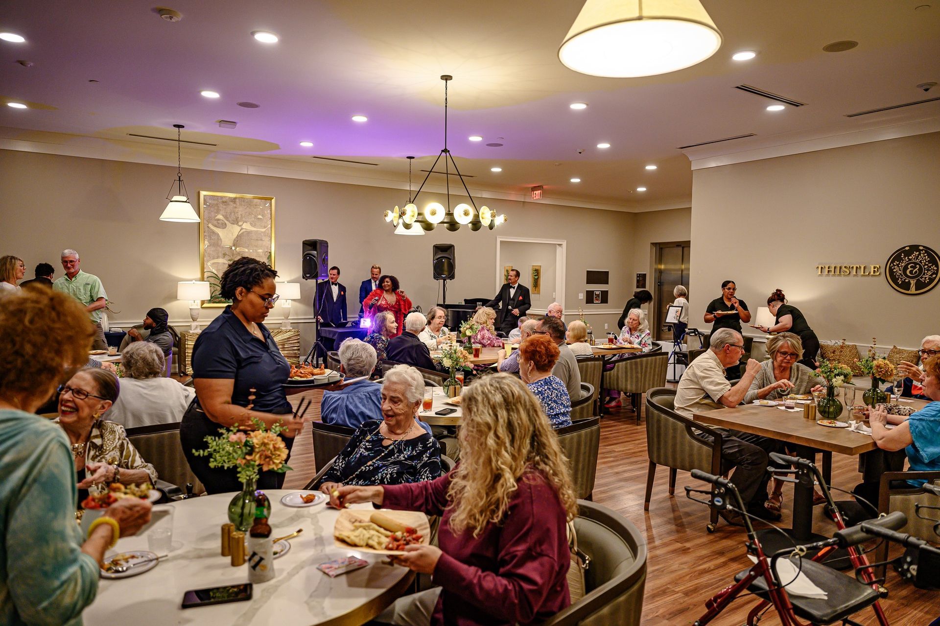 A large group of people are sitting at tables in a dining room.