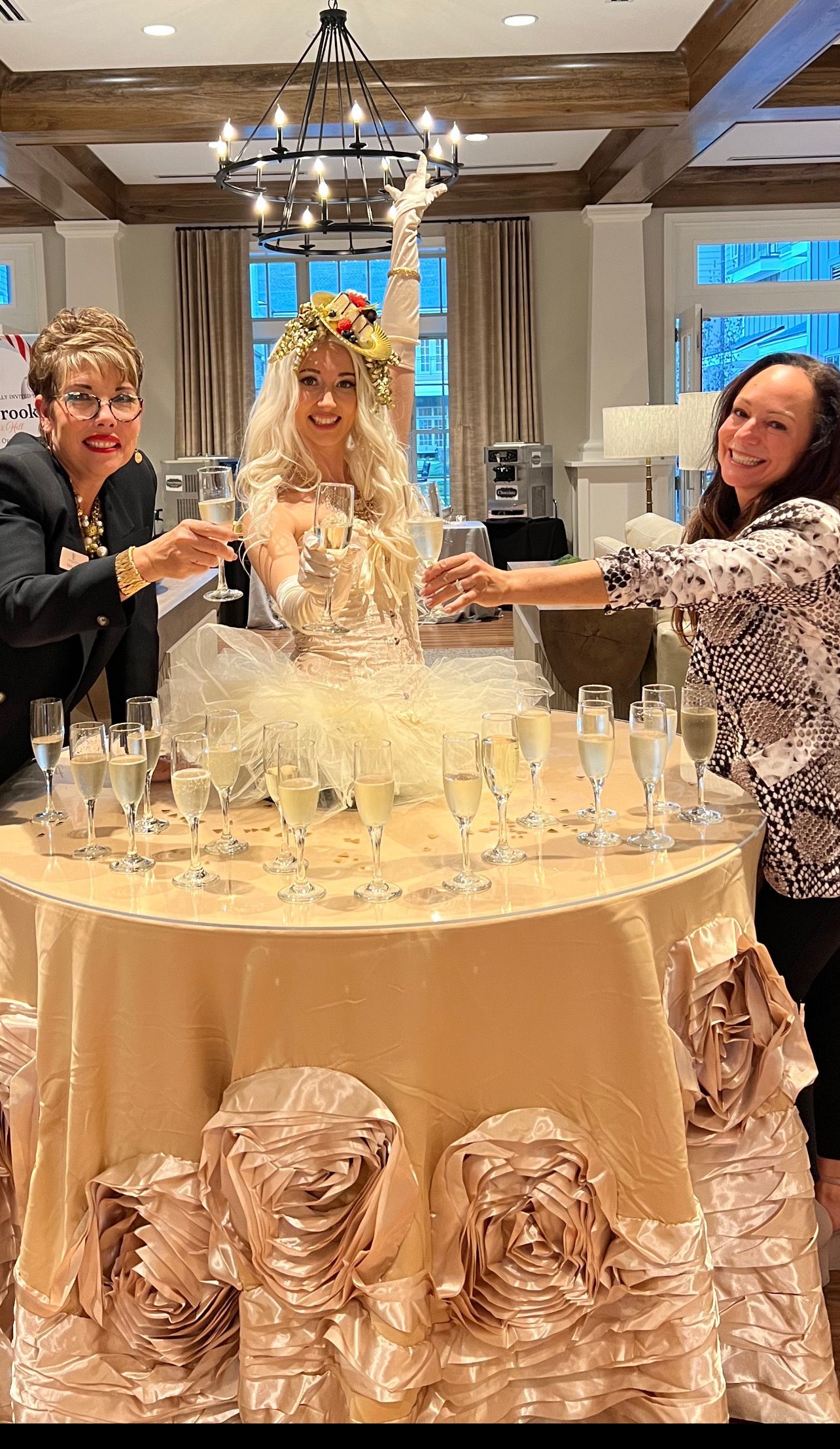 A group of women are standing around a table filled with champagne glasses.