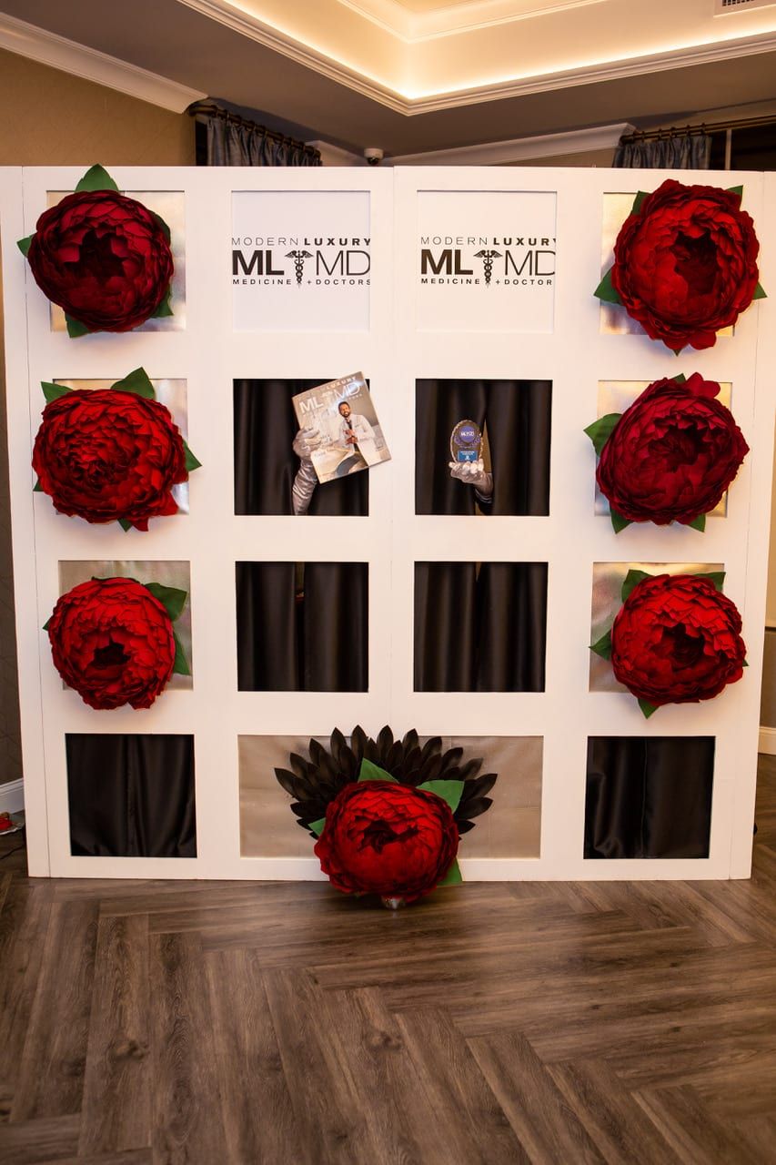 White display wall with red floral wreaths and branded panels in a modern indoor event setting