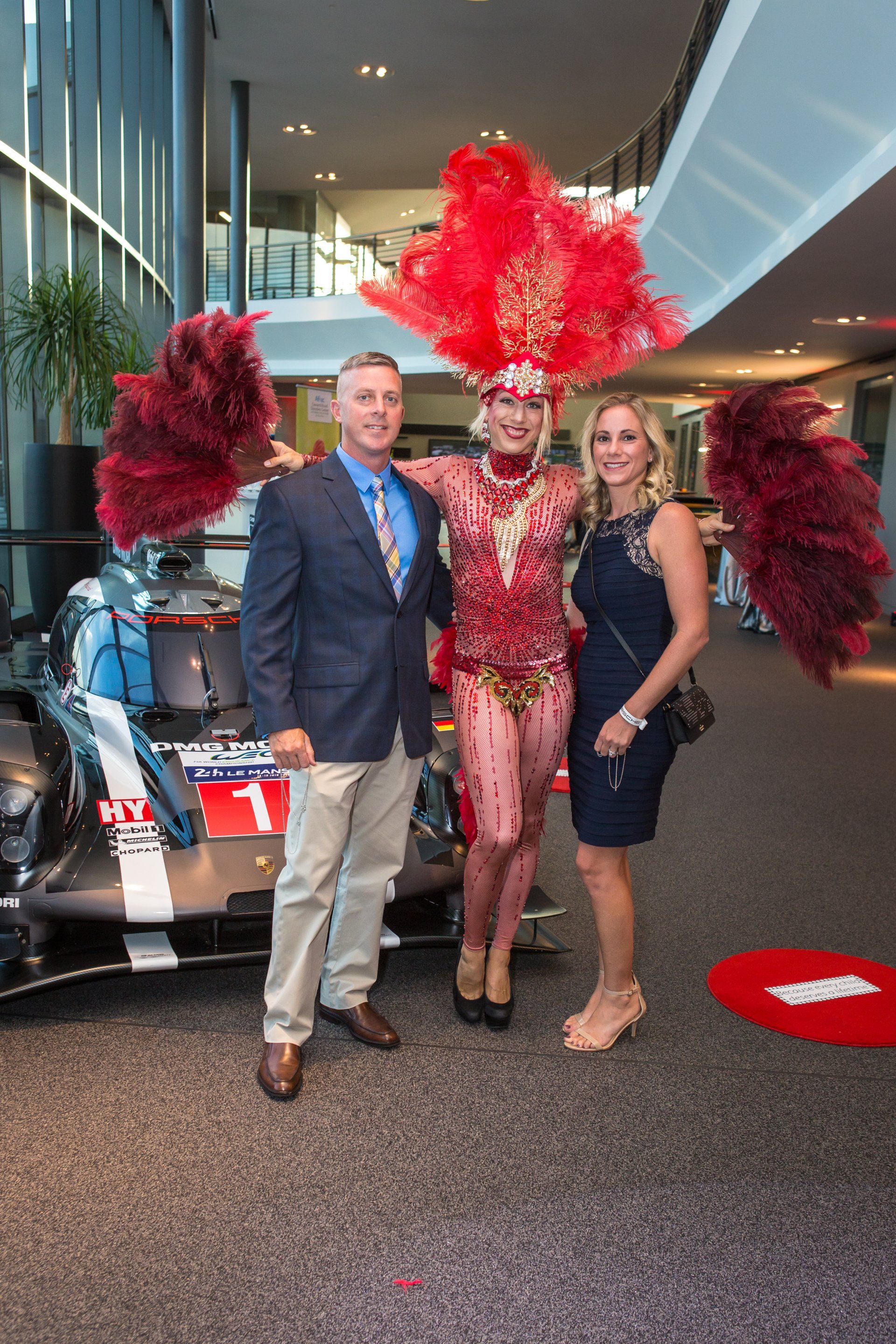 A man and two women are posing for a picture in front of a race car.