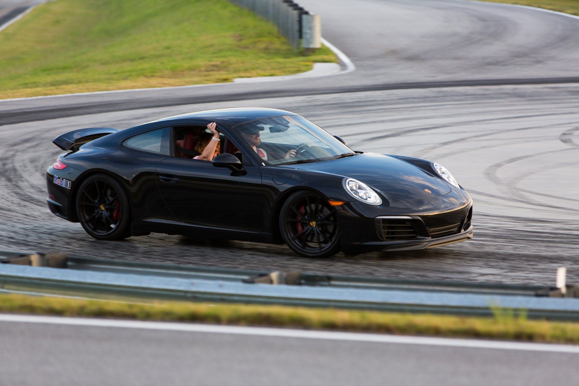 A black porsche 911 is driving on a race track.