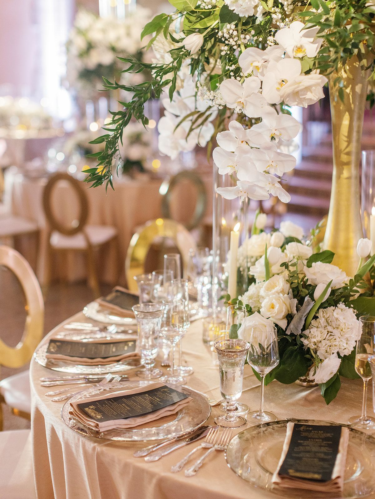 A table set for a wedding reception with plates , silverware , candles and flowers.