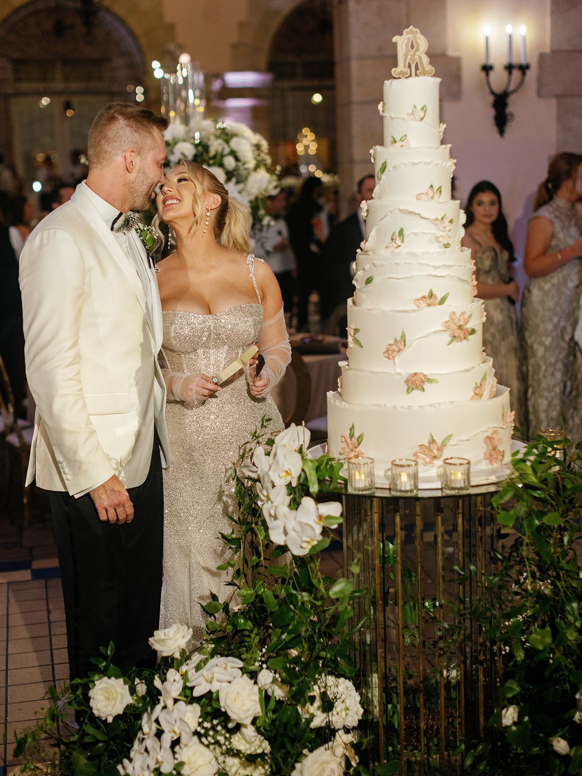 A bride and groom are standing in front of a wedding cake.