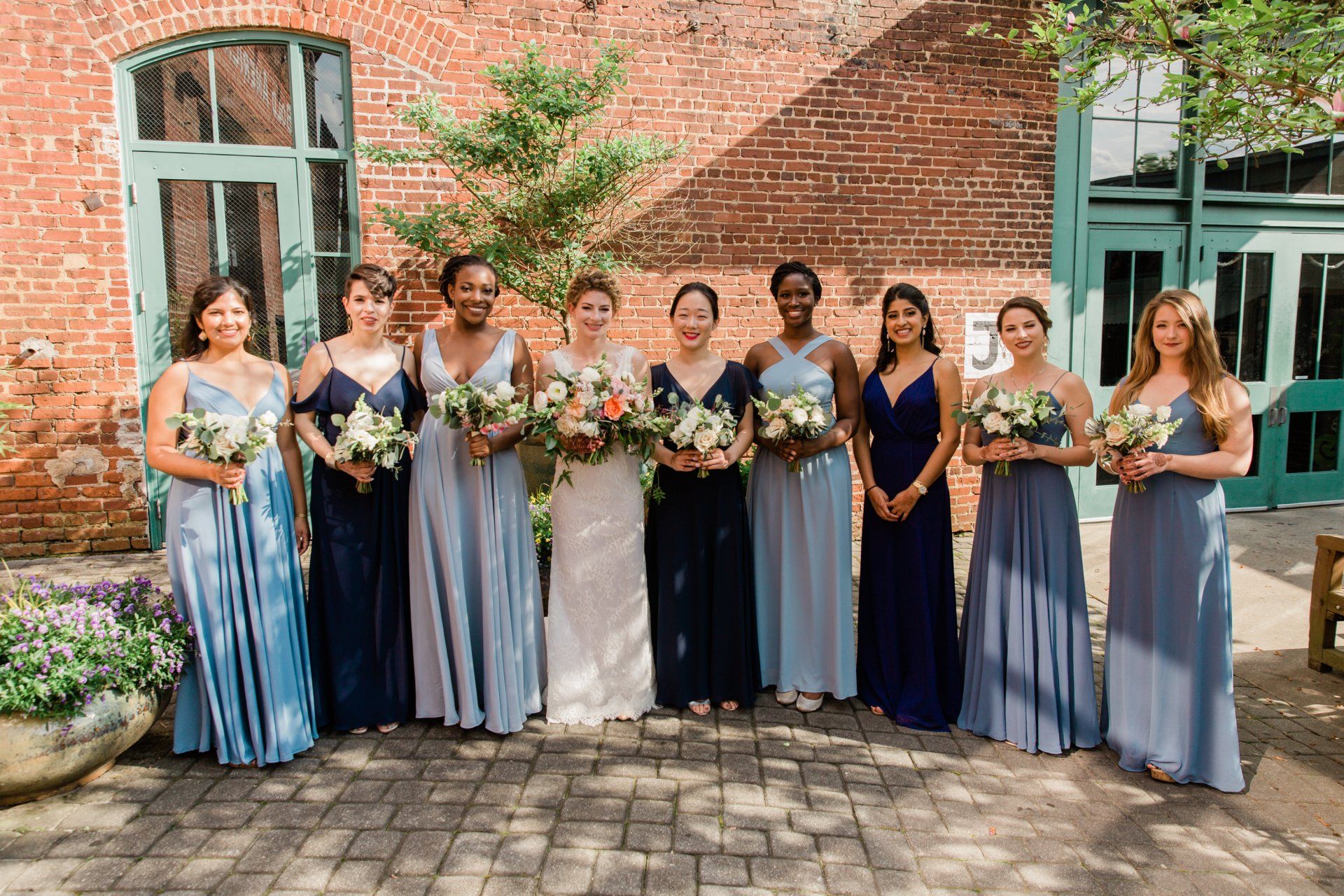 A bride and her bridesmaids are posing for a picture in front of a brick building.