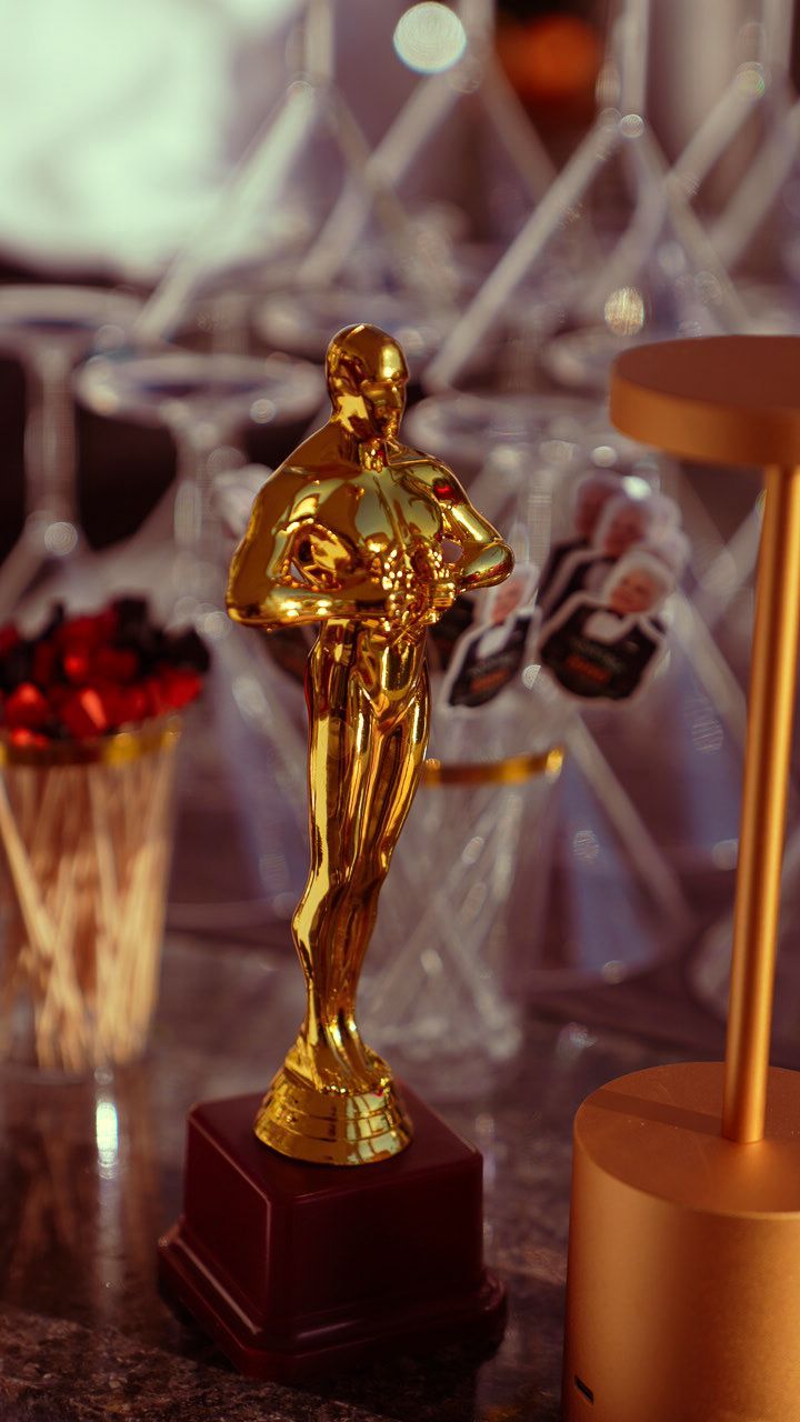 Gold statuette trophy on a dark base, with other awards blurred in the background.