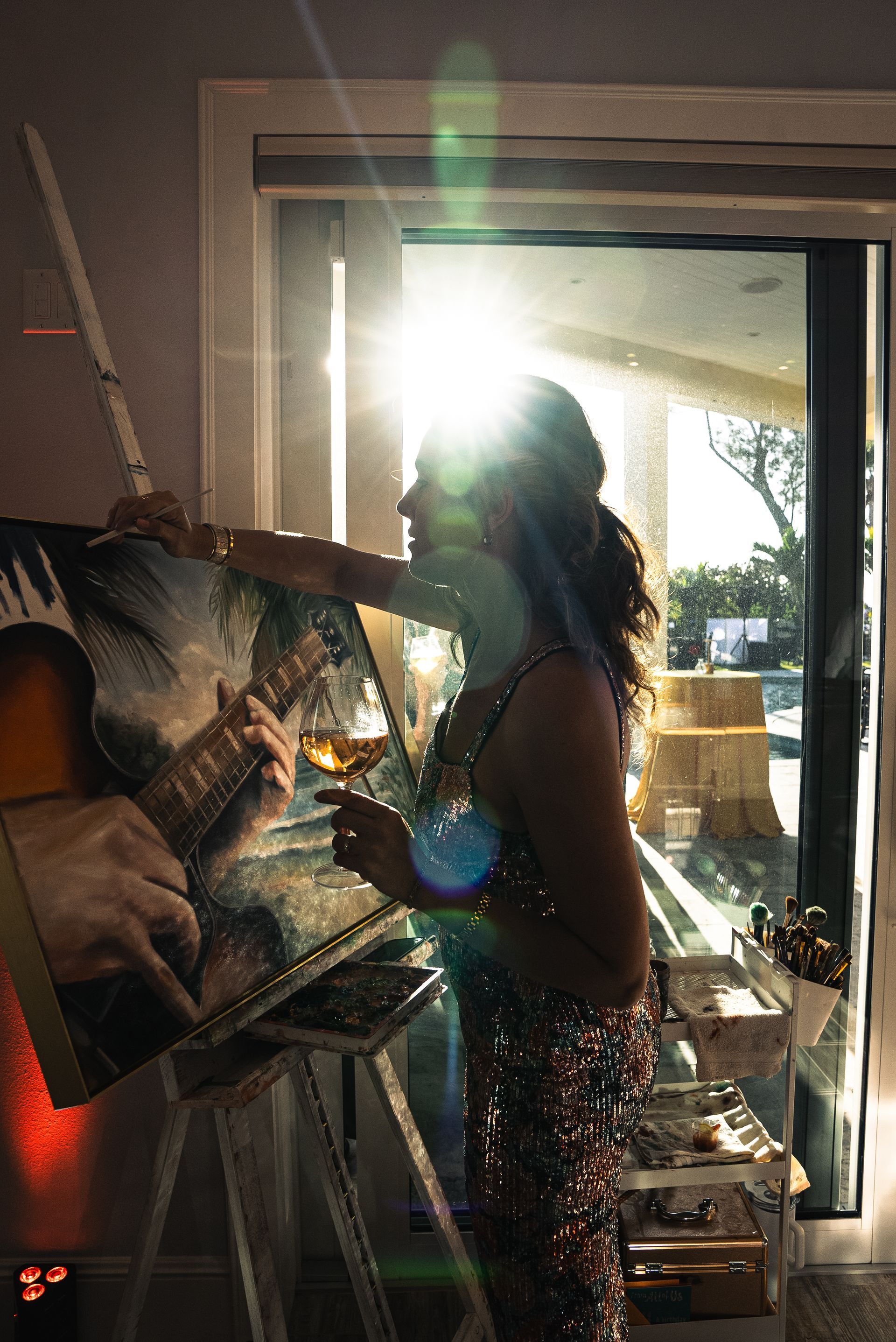 Backlit person standing in a doorway, holding an acoustic guitar in a cluttered room
