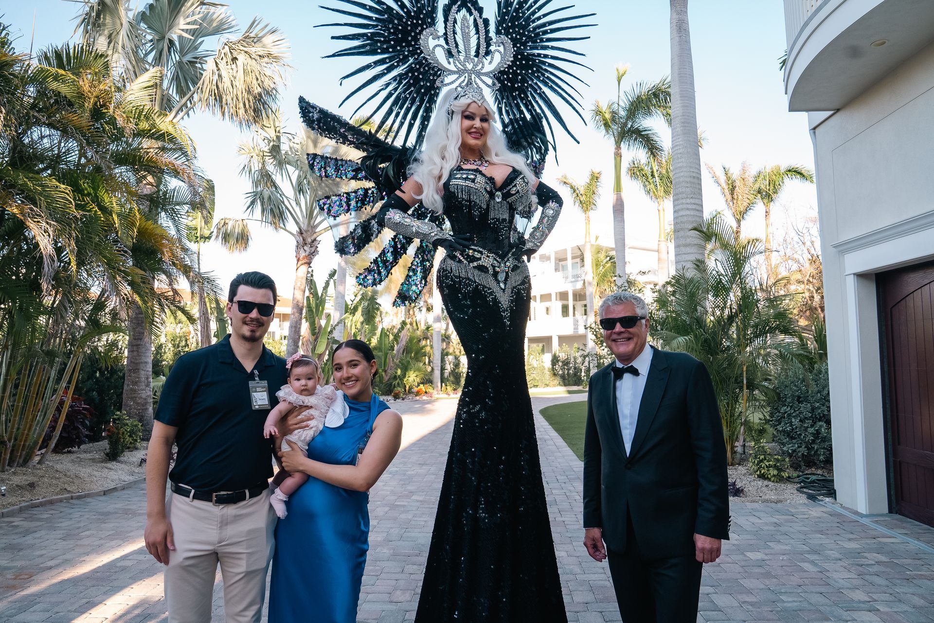 Group posing beside a towering black-and-white sculpture on a sunny palm-lined street