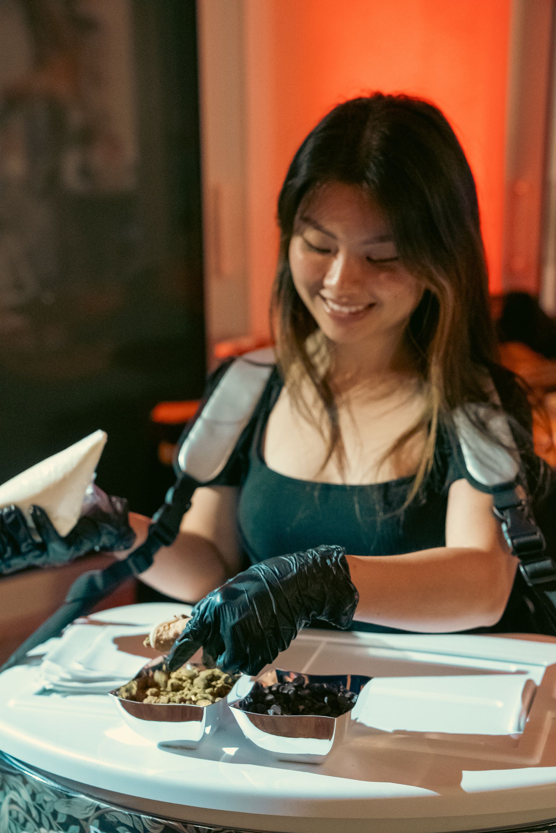 Person smiling at a candlelit table, holding a lobster dish in a restaurant.