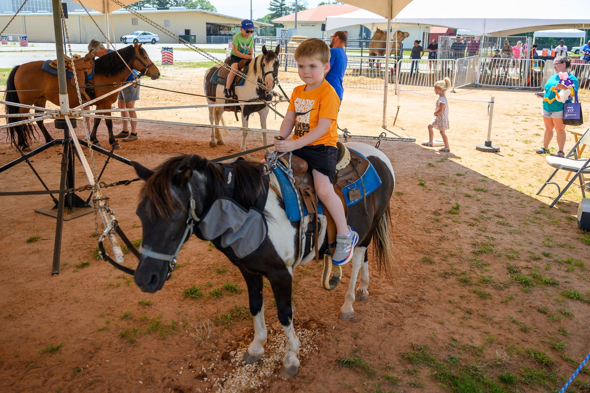 A young boy is riding a pony in a dirt field.