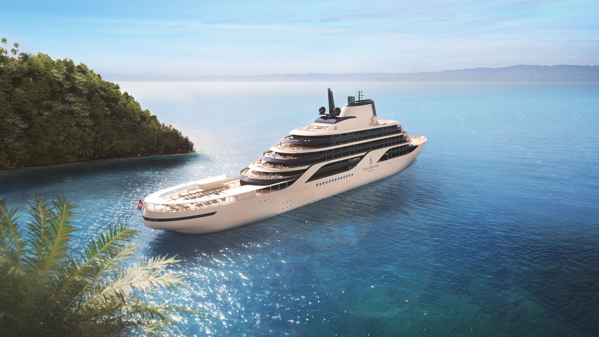 Luxury white yacht cruising on clear blue water near a tropical island shoreline