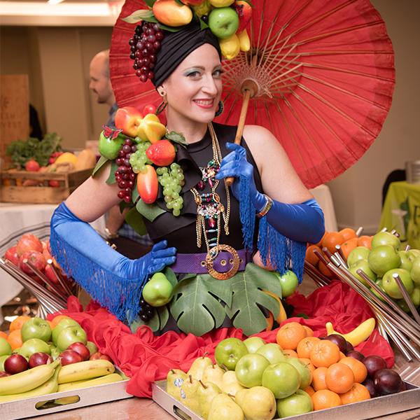 A woman holding an umbrella surrounded by fruits and vegetables