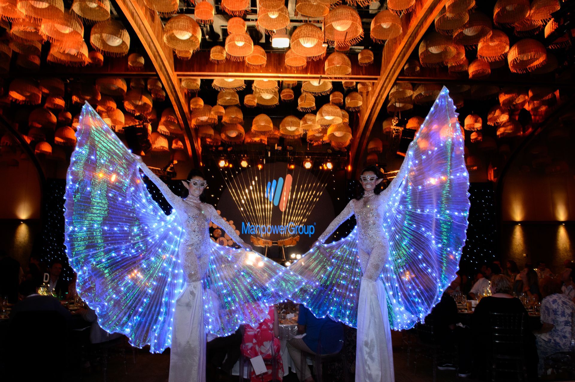 two women wearing light up wings are standing in a room .