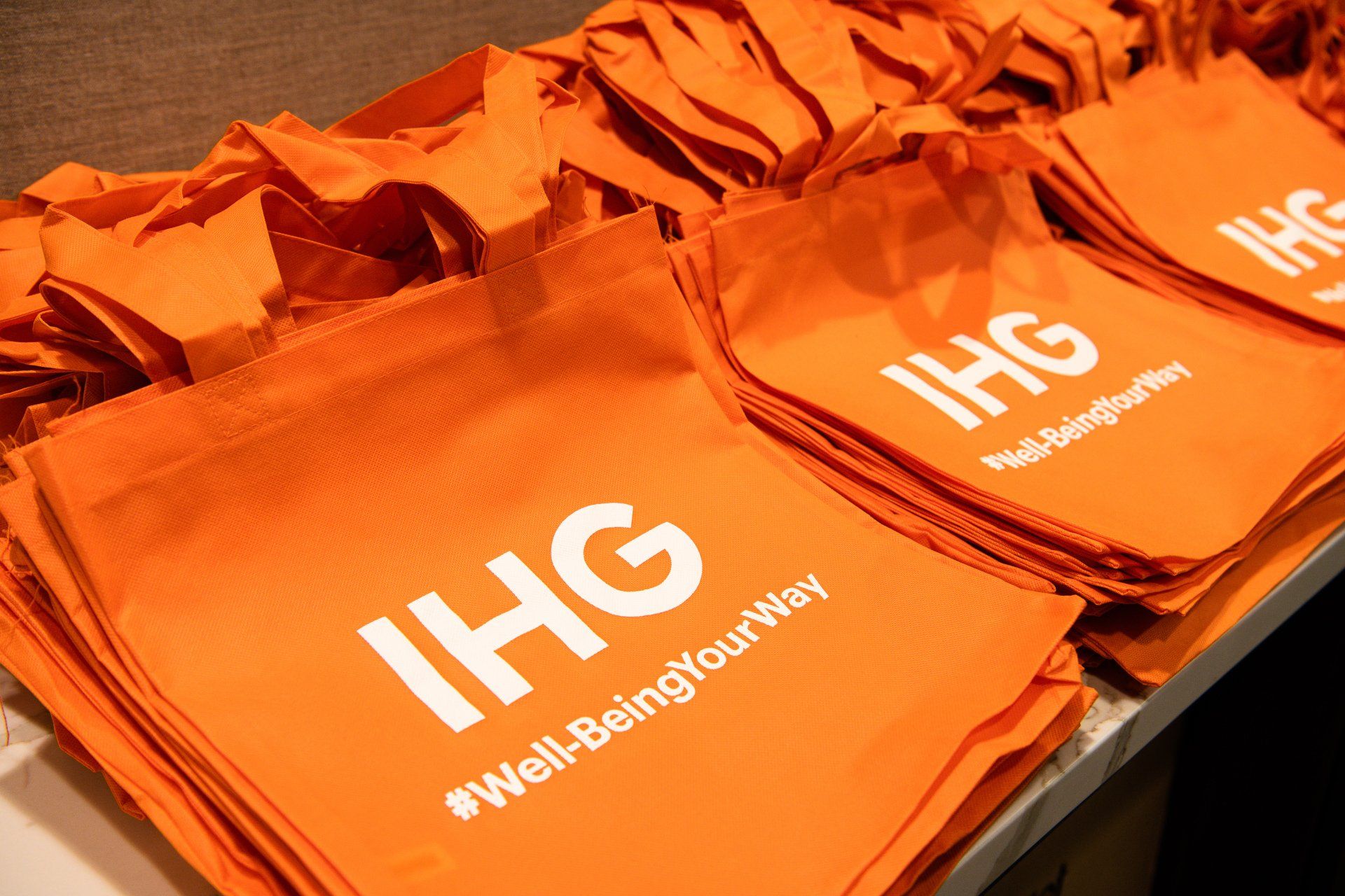 A bunch of orange ihg bags are stacked on top of each other