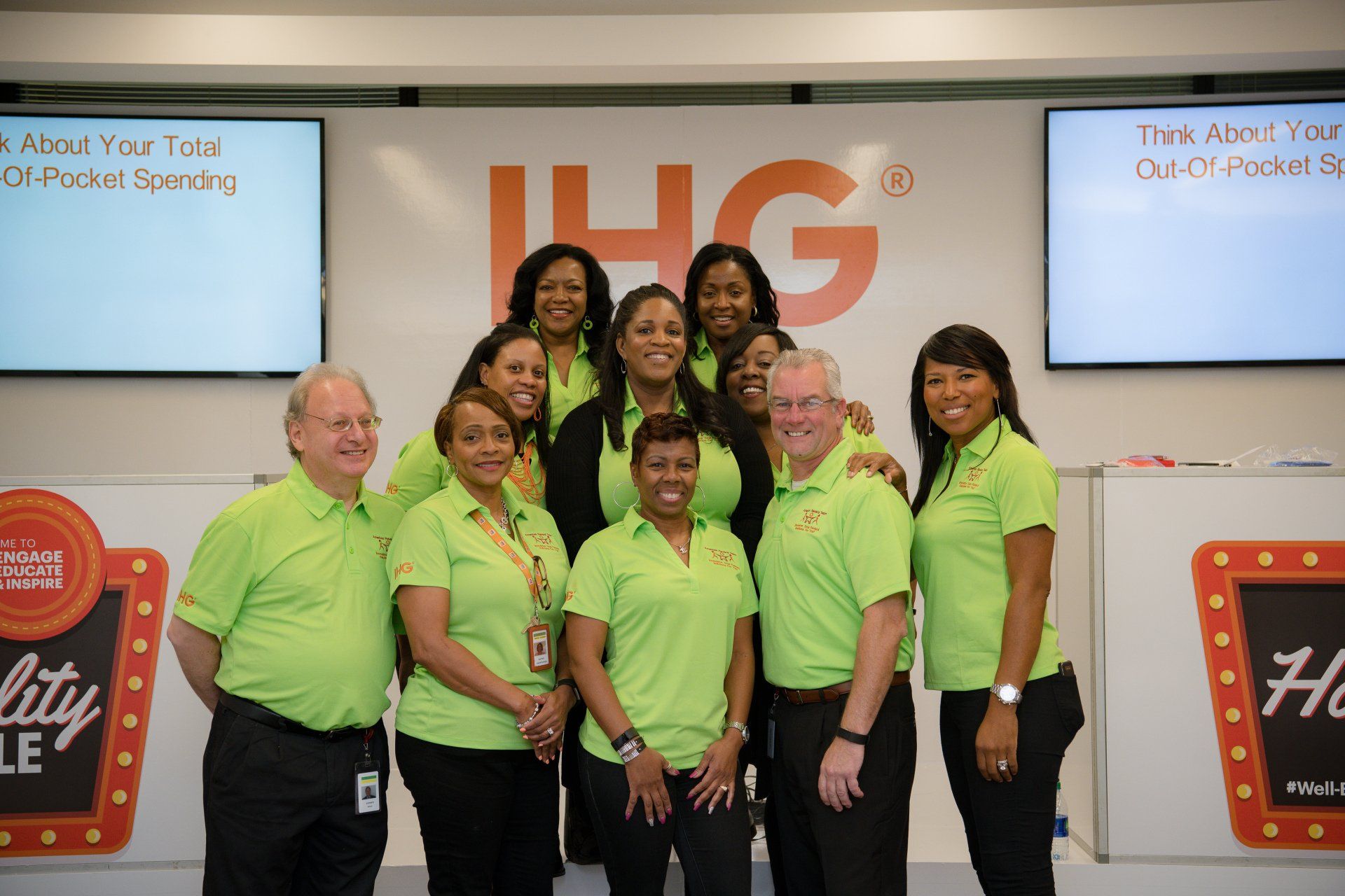 A group of people wearing green shirts are posing for a picture.