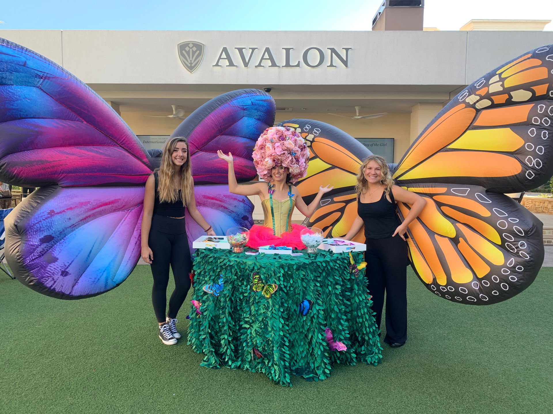 three women dressed as butterflies are standing around a table .
