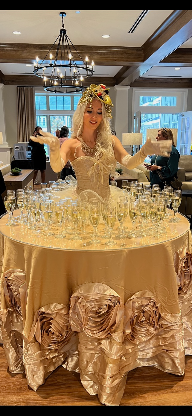 A woman is standing in front of a table filled with champagne glasses.