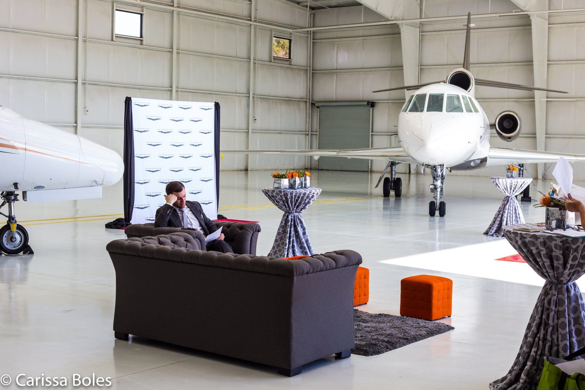 a man is sitting on a couch in a hangar with a plane in the background .