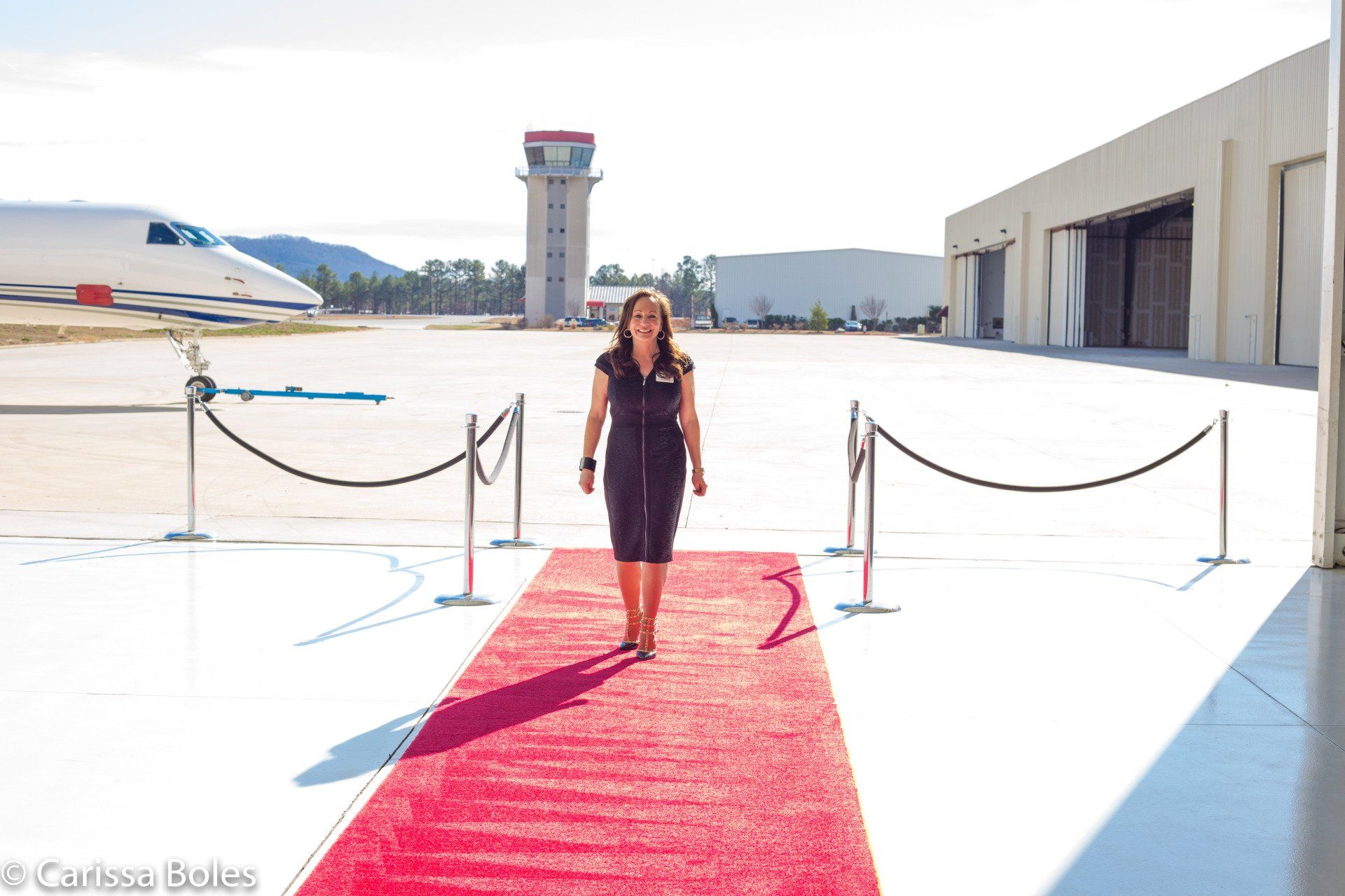 a woman is walking on a red carpet in front of an airplane