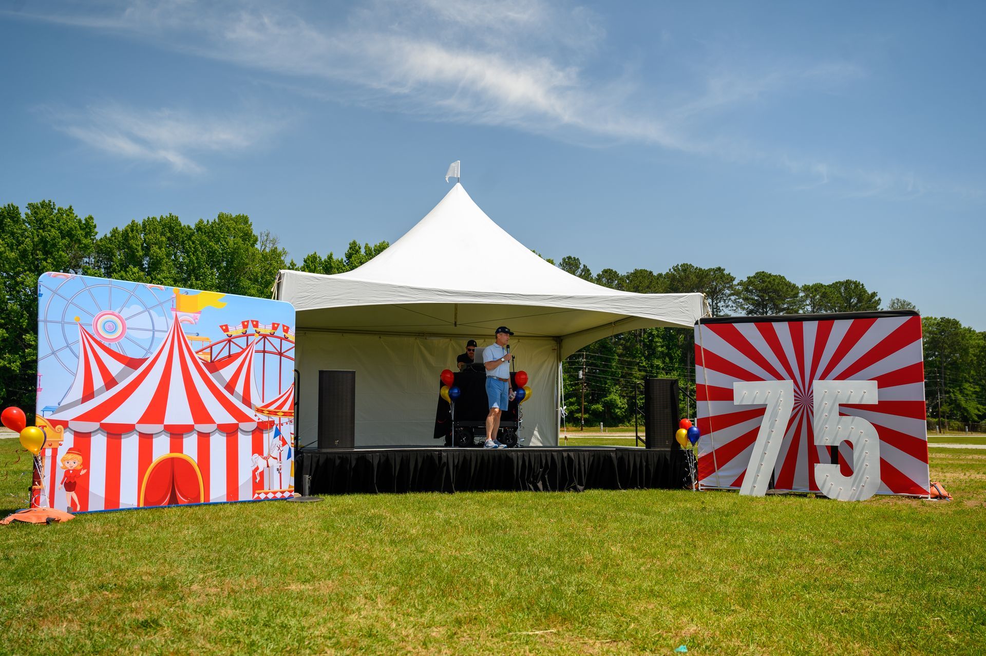 A man is standing on a stage in front of a tent.
