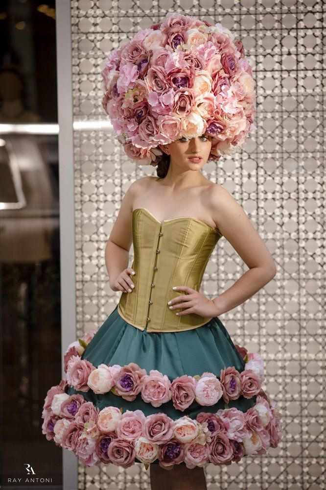 A woman is wearing a dress and a hat made of flowers.